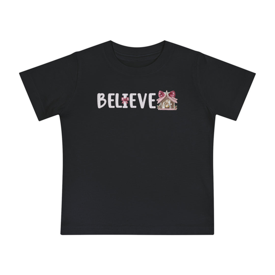 Believe Baby Tee features BELIEVE in white, with a pink-bow I and gingerbread-house E, on a soft, durable black T-shirt.