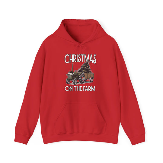 Christmas at the Farm Hoodie features a tractor pulling a Christmas tree on a red hoodie with a kangaroo pocket, promoting warmth and comfort.