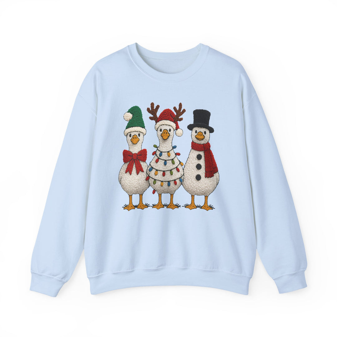 Light-blue crewneck sweatshirt featuring three festive cartoon geese in holiday attire: stocking-cap, reindeer antlers, and snowman style, offering cozy comfort and durability.