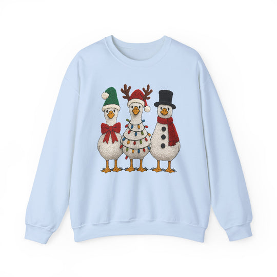 Light-blue crewneck sweatshirt featuring three festive cartoon geese in holiday attire: stocking-cap, reindeer antlers, and snowman style, offering cozy comfort and durability.