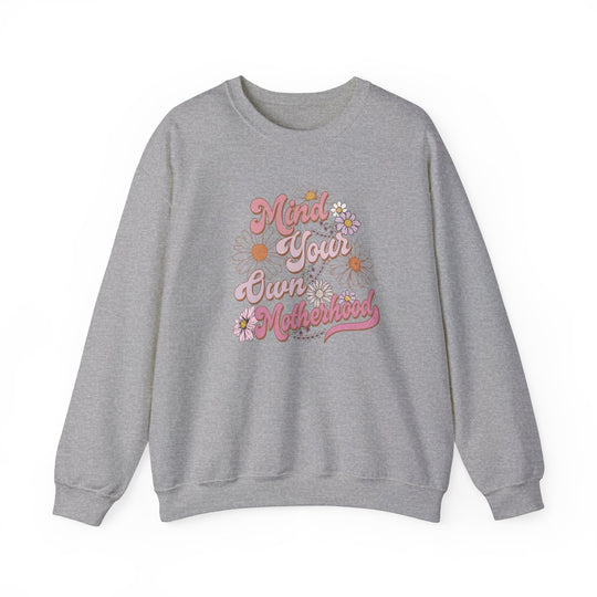 A unisex heavy blend crewneck sweatshirt, Mind Your Own Motherhood Crew, in grey with pink text. Made of 50% cotton, 50% polyester, ribbed knit collar, no itchy side seams, loose fit.
