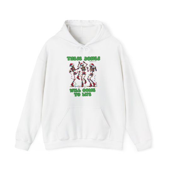 White hoodie with dancing skeletons in Christmas lights, Santa hats, and green text saying “THESE BONES WILL COME TO LIFE” with “Ezekiel 37:4-5” reference.