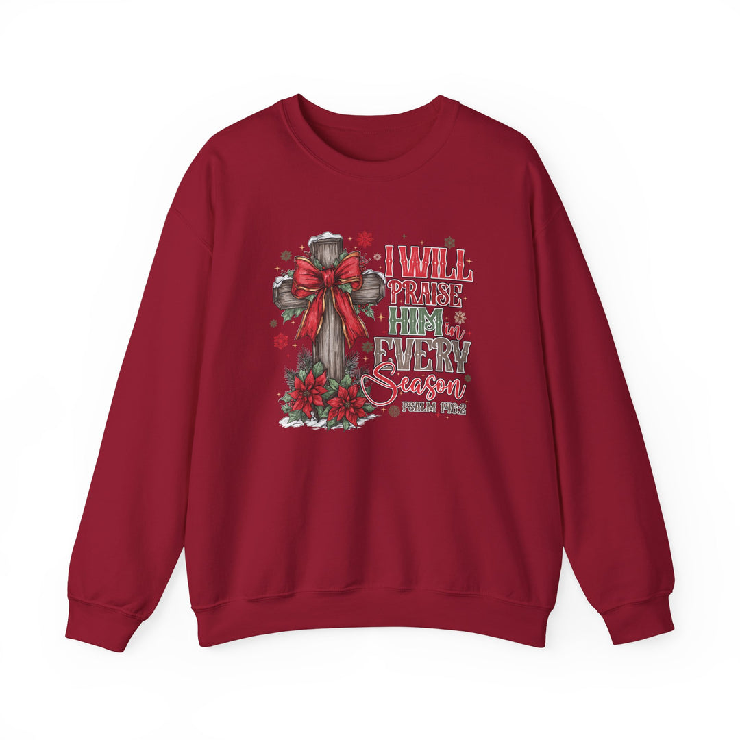 Red crew-neck sweatshirt featuring a festive cross with bow, poinsettias, snowflakes, and Psalm 146:2 text: Praise Him in Every Season.
