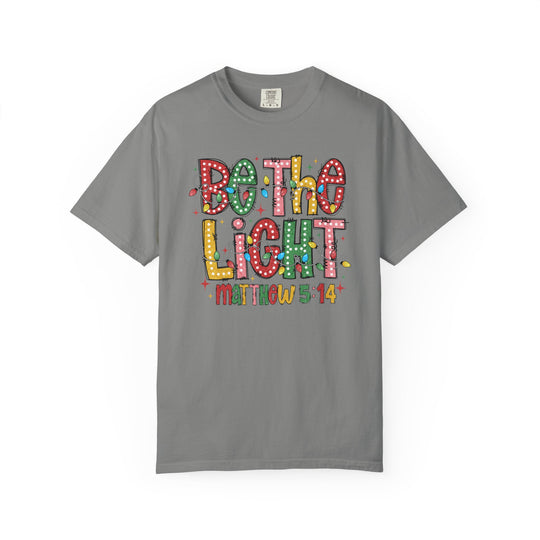 Heather-gray Be the Light Tee with festive lettering and Christmas bulbs design, featuring Bible reference Matthew 5:14. Available in sizes S to 4XL.