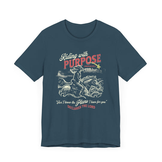 Riding for a Purpose Tee: Blue t-shirt featuring a graphic of a cowboy riding a horse, crafted from soft cotton with a comfortable retail fit.
