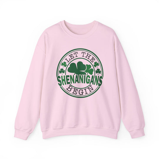 Let the Shenanigans Begin Day Crew sweatshirt featuring green text and clover logo on a pink background, ideal for casual comfort and style.