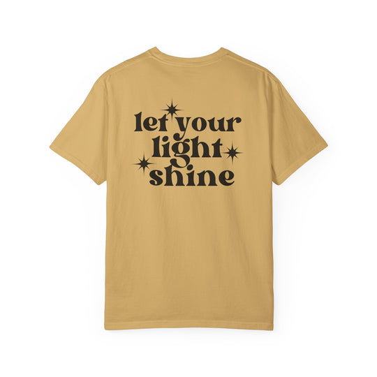 Let Your Light Shine Tee: Tan shirt with black text, 100% ring-spun cotton, garment-dyed for coziness, relaxed fit, double-needle stitching for durability, no side-seams for shape retention.