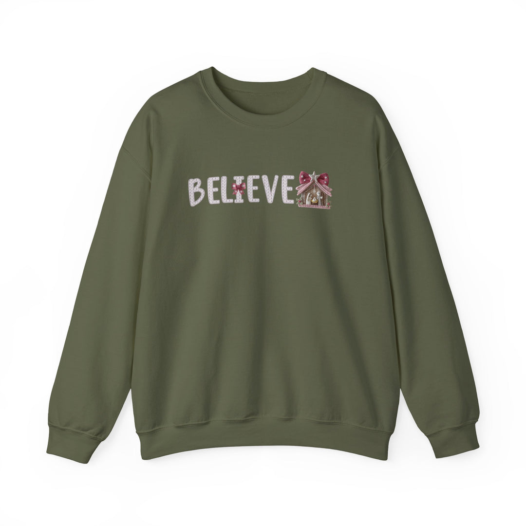 Olive-green crewneck sweatshirt with BELIEVE in chunky font, featuring a festive gingerbread-style stable motif. Perfect for cozy, holiday-inspired wear.