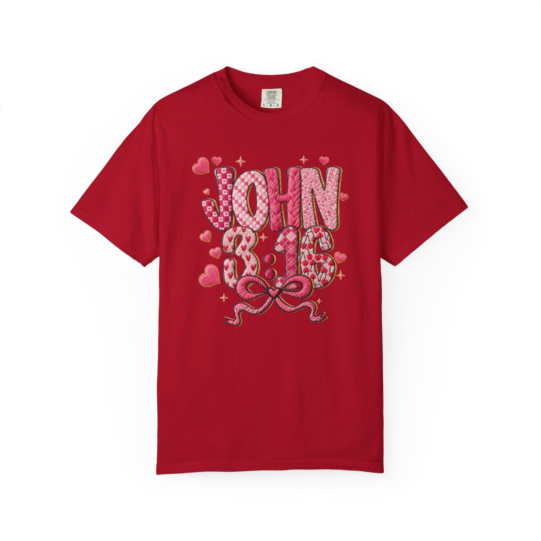 Red crew-neck T-shirt featuring JOHN 3:16 in patchwork letters with heart patterns, sparkles, and a ribbon bow, highlighting Faith Family Designs' unique graphic style.