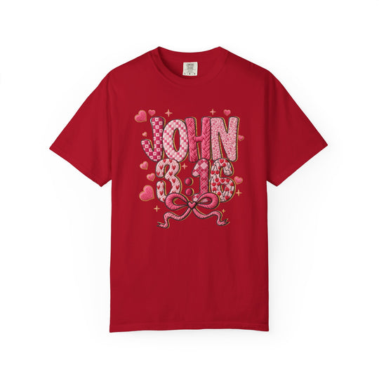Red crew-neck T-shirt featuring JOHN 3:16 in patchwork letters with heart patterns, sparkles, and a ribbon bow, highlighting Faith Family Designs' unique graphic style.