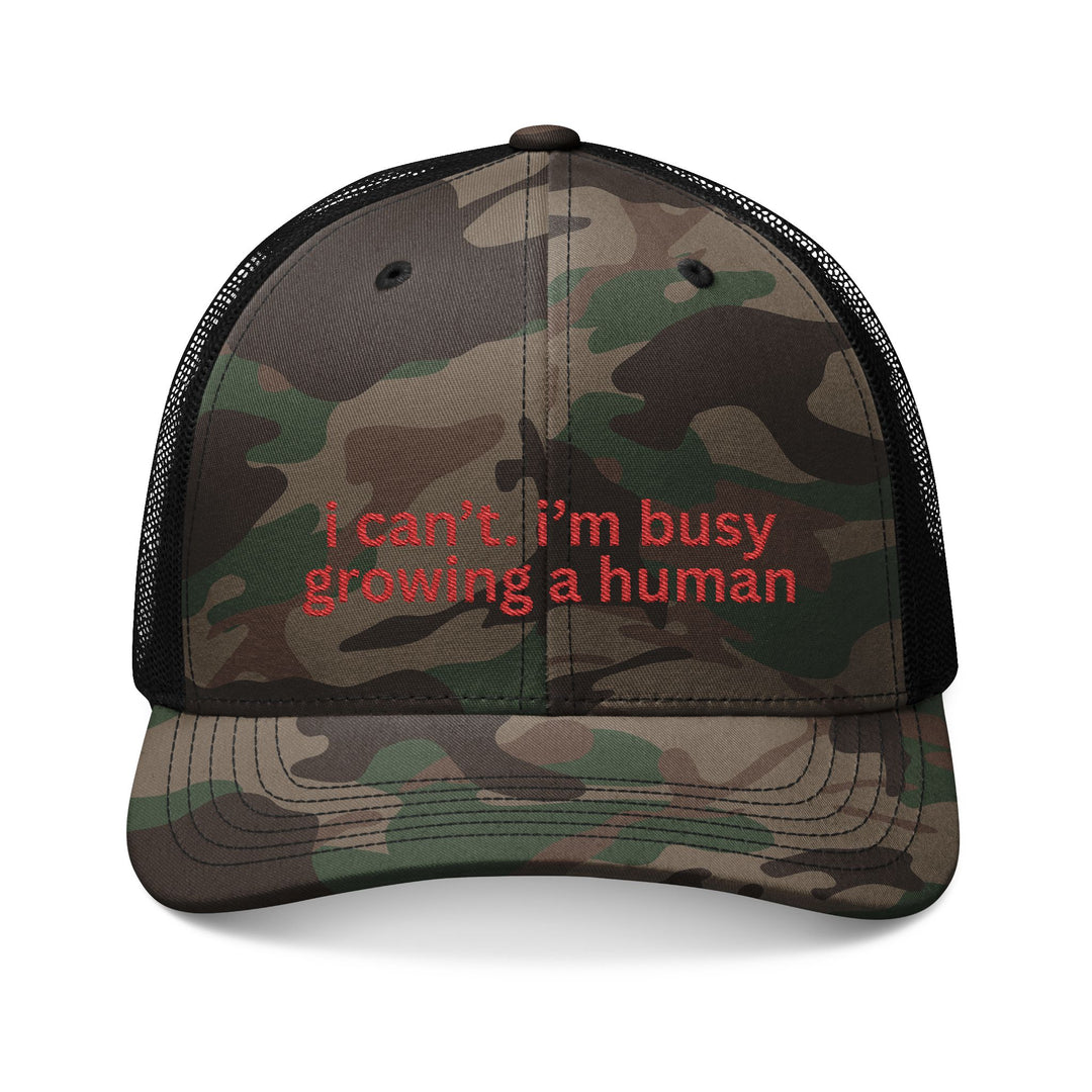 Camouflage-patterned trucker hat with mesh back, embroidered with i can’t. i’m busy growing a human. in red, from Faith Family Designs.
