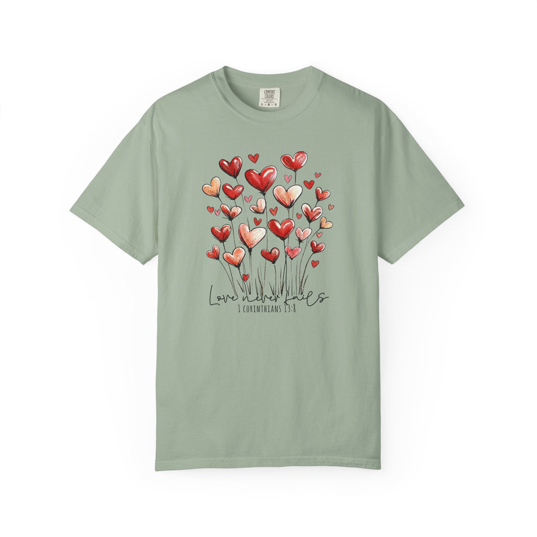Love Never Fails Tee featuring heart-shaped flowers and scriptural quote; short-sleeve, sage-green, Comfort Colors brand.