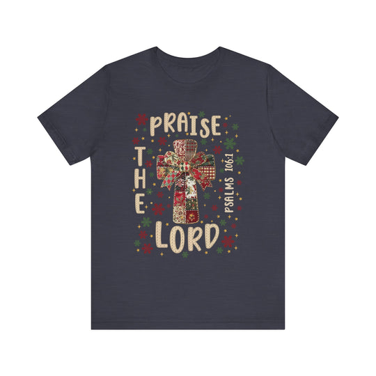 Navy Praise the Lord Tee with festive cross, bow, stars, and snowflakes, featuring Psalms 106:1 in a knitted-yarn style.