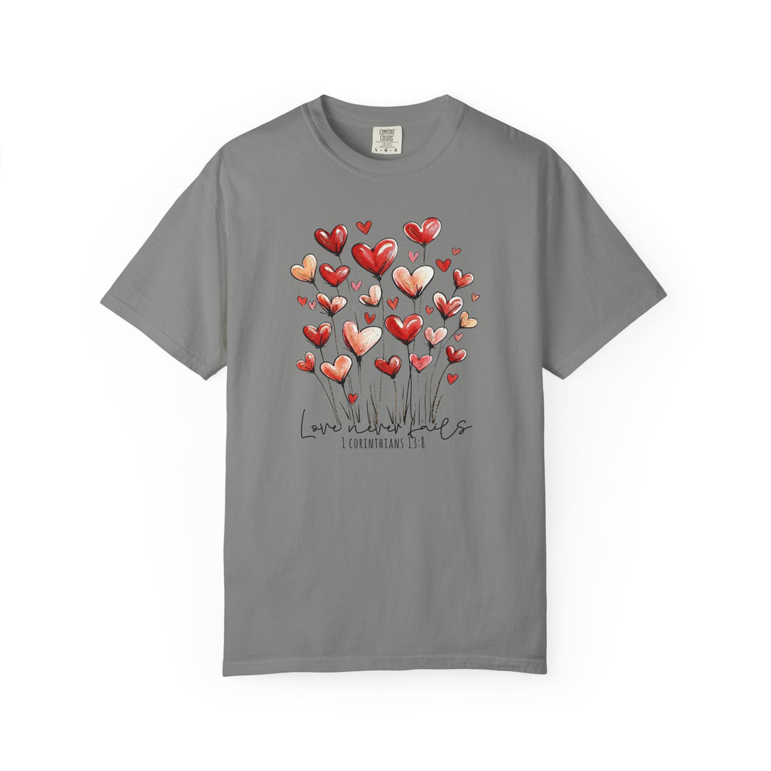 Love Never Fails Tee featuring heart-shaped blooms and scripture text on a heather-gray Comfort Colors short-sleeve shirt, embodying a message of enduring love.