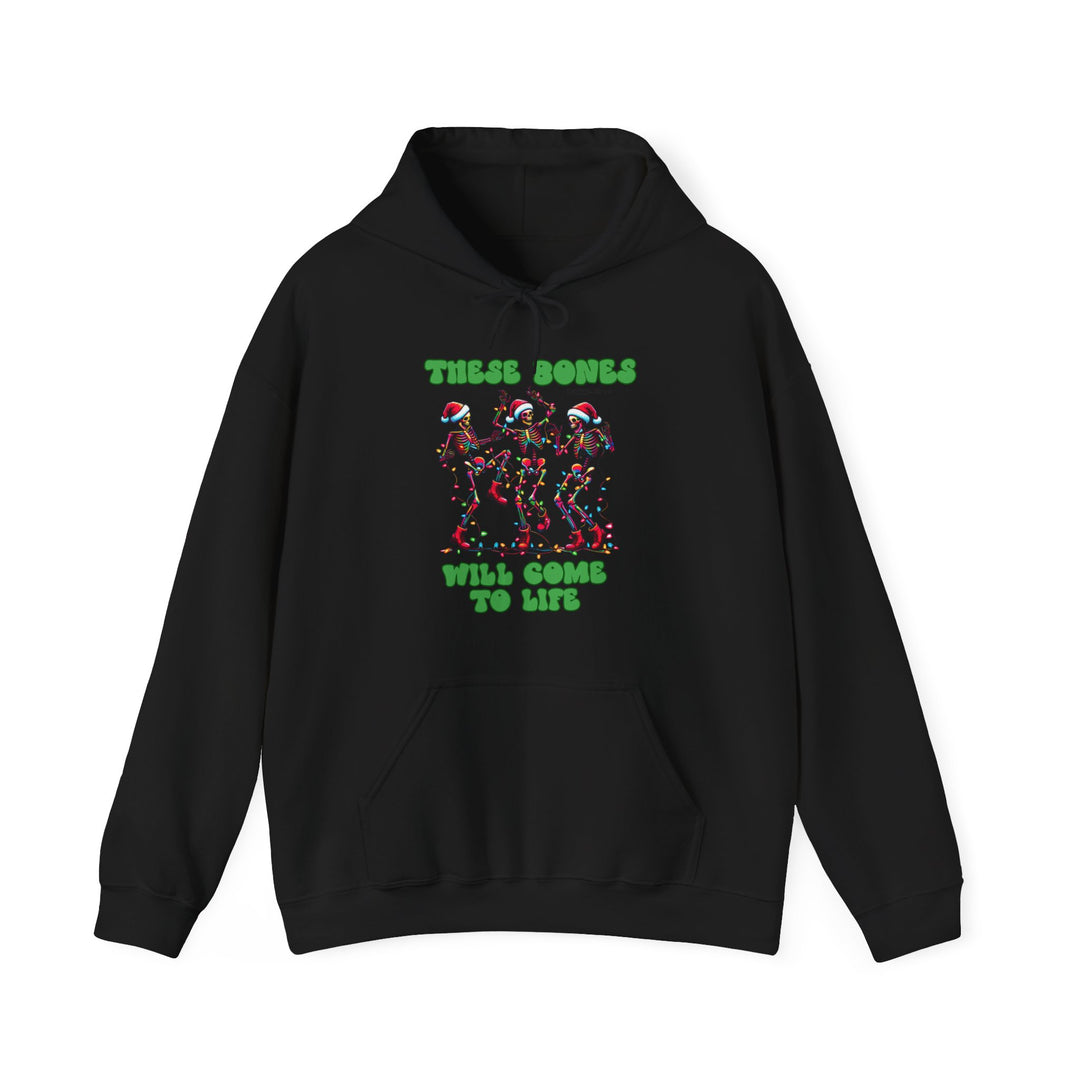 Black hoodie with festive graphic: three dancing skeletons in Santa hats and Christmas lights, text These Bones Will Come To Life. Cozy cotton-polyester blend.