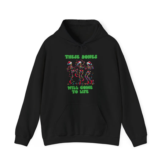 Black hoodie with festive graphic: three dancing skeletons in Santa hats and Christmas lights, text These Bones Will Come To Life. Cozy cotton-polyester blend.