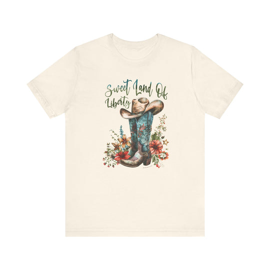 A white t-shirt featuring a cowboy hat and boots, embodying a classic Americana vibe. Made of 100% Airlume combed cotton, with ribbed knit collars and taping on shoulders for lasting comfort. Sweet Land of Liberty Tee by Worlds Worst Tees.
