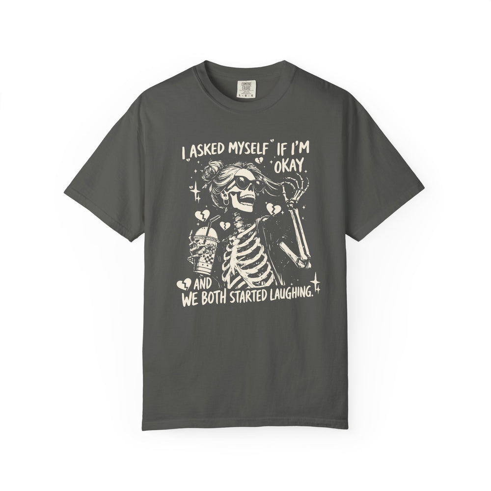 Charcoal T-shirt featuring a cartoon skeleton with sunglasses, messy bun, holding a drink, surrounded by sparkles and broken hearts. Text: I ASKED MYSELF IF I’M OKAY AND WE BOTH STARTED LAUGHING.”
