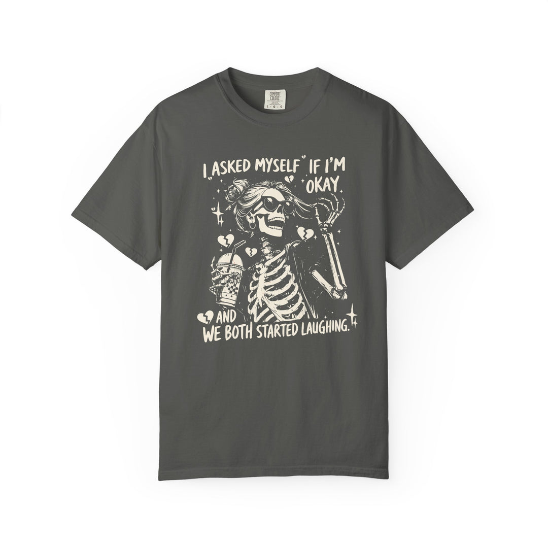 Charcoal T-shirt featuring a cartoon skeleton with sunglasses, messy bun, holding a drink, surrounded by sparkles and broken hearts. Text: I ASKED MYSELF IF I’M OKAY AND WE BOTH STARTED LAUGHING.”