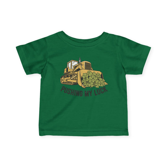 Pushing My Luck Baby Tee: Green infant T-shirt featuring a yellow bulldozer illustration with four-leaf clovers and PUSHING MY LUCK text, designed for comfort and durability.