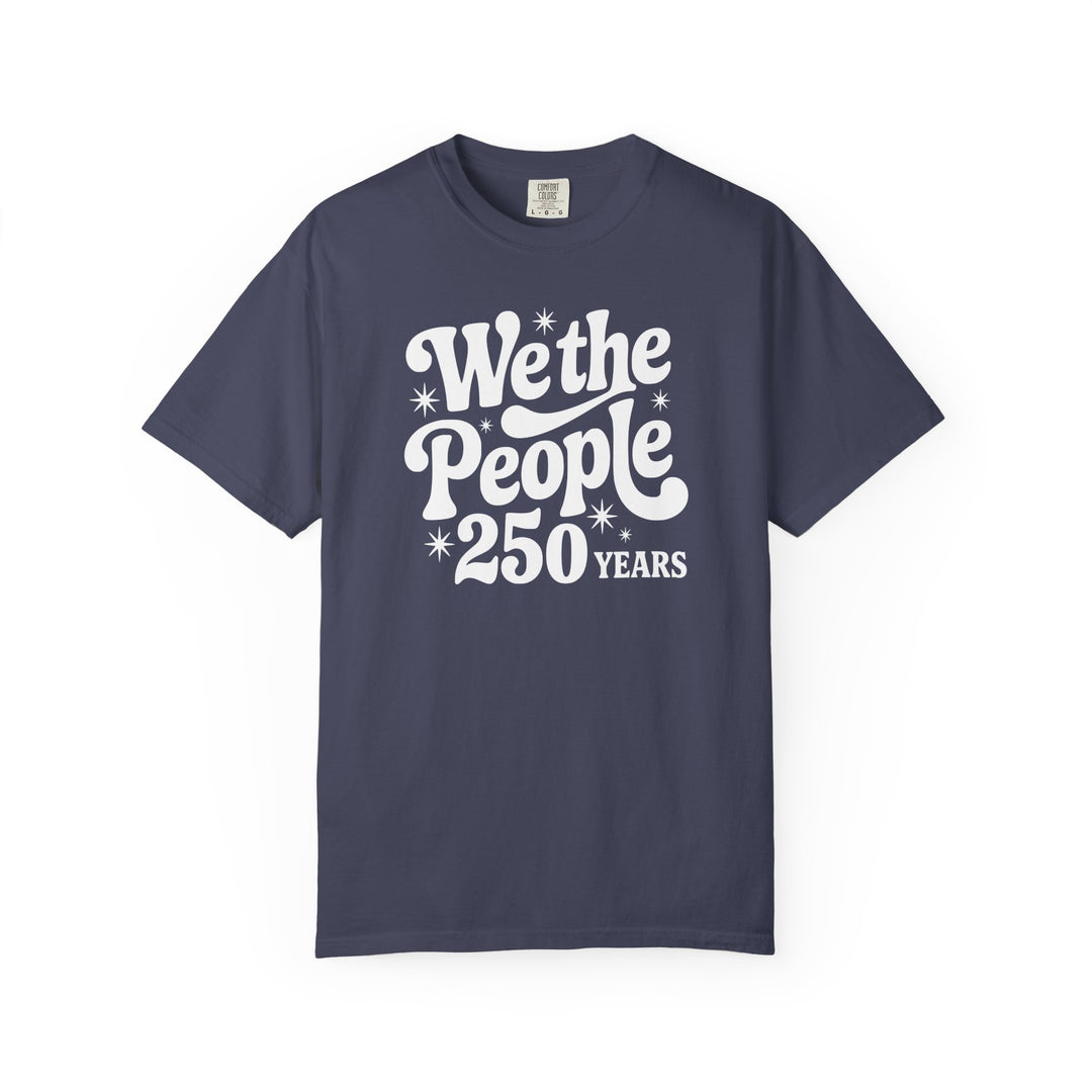 We the People Tee features retro-style white lettering with starburst accents on a navy-blue Comfort Colors T-shirt, offering a relaxed, durable fit in multiple sizes.