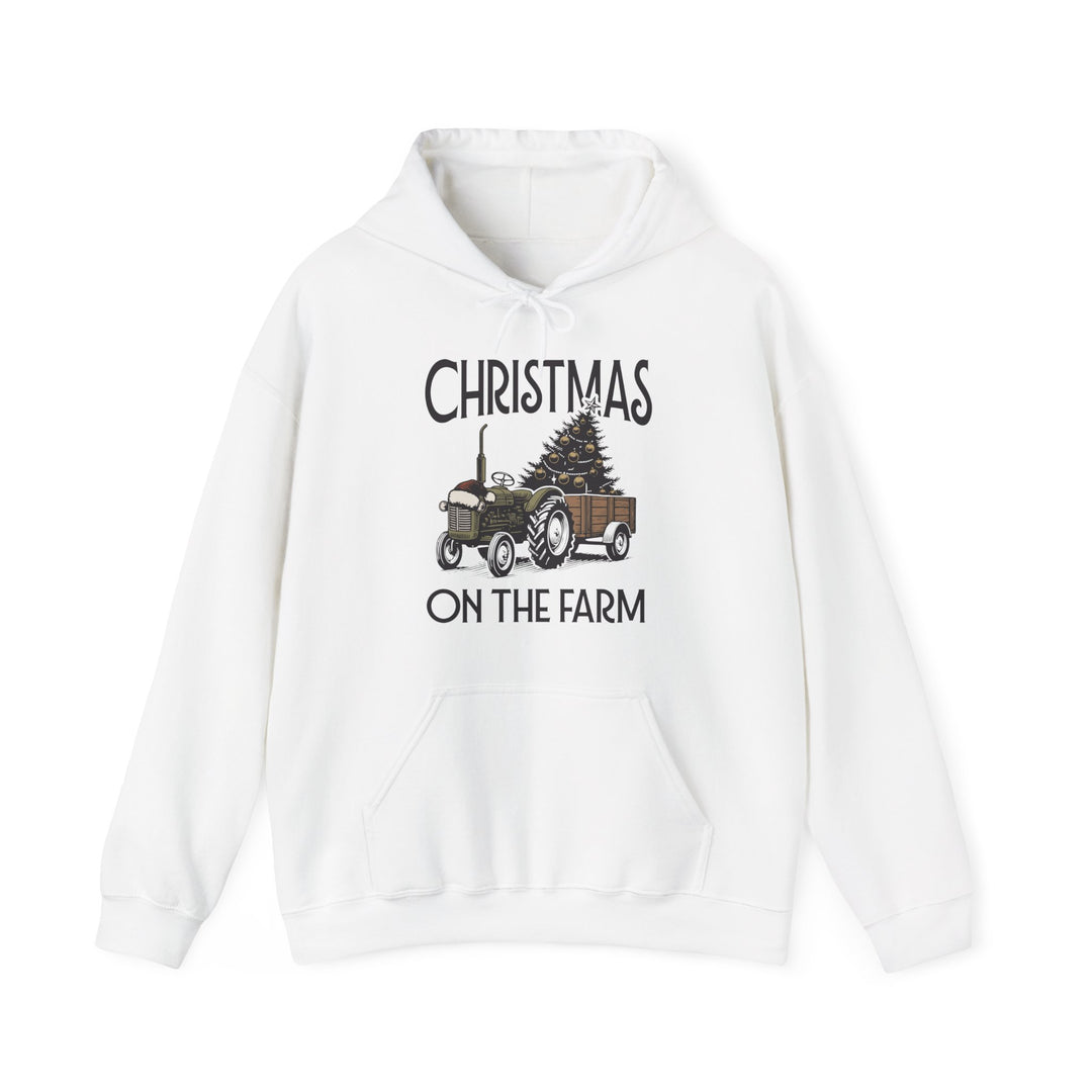 White pullover hoodie featuring Christmas at the Farm design with a vintage green tractor towing a trailer carrying a decorated Christmas tree.
