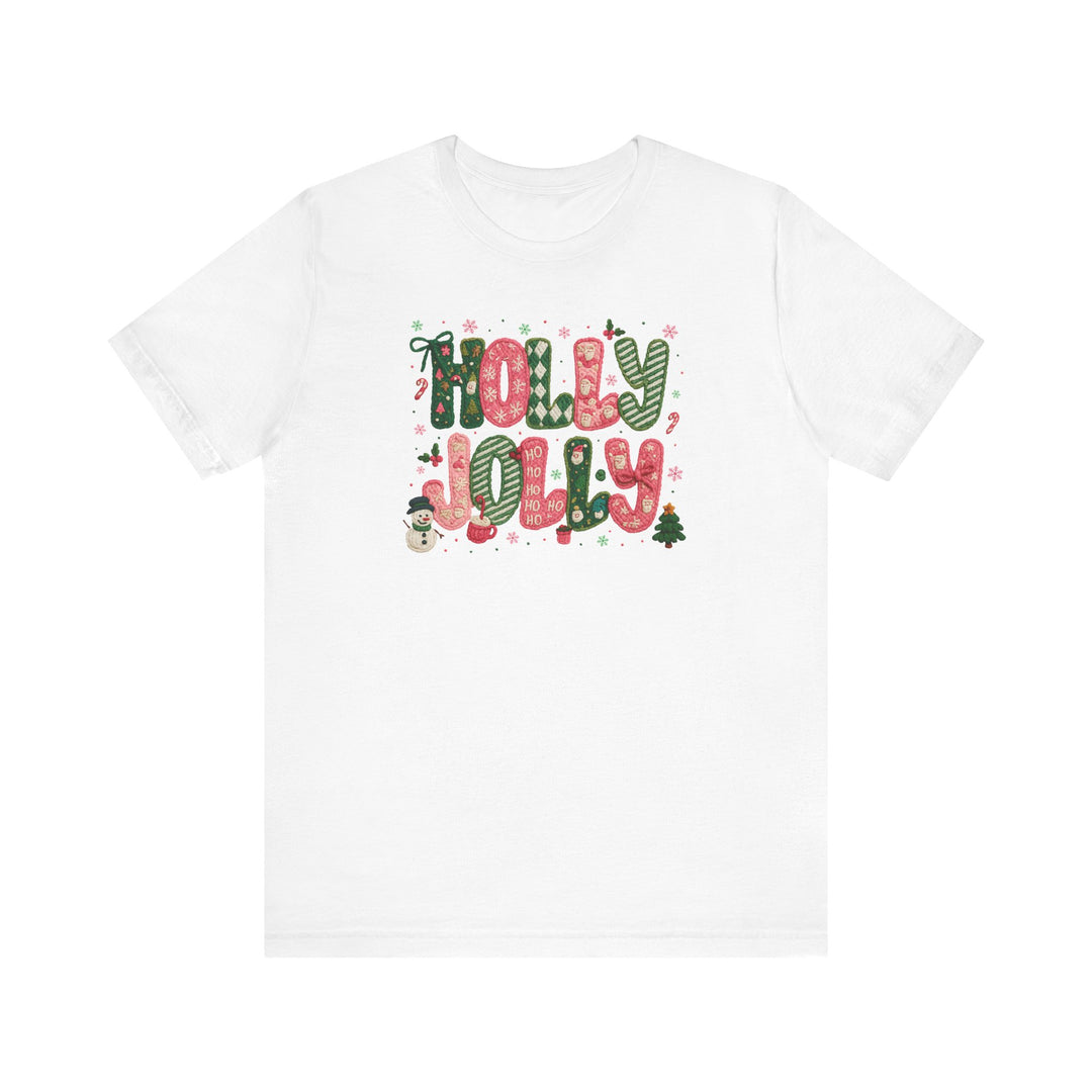 Holly Jolly Tee: White crew-neck T-shirt with festive HOLLY JOLLY graphic, featuring candy-cane-and-plaid letters, holiday icons, and snowflakes for a cheerful Christmas vibe.