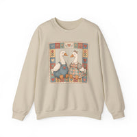 Thrifted Geese Crew: Unisex beige sweatshirt featuring two folk-art geese in clothes, framed by a heart and flower quilt-like border. Cozy, loose fit, cotton-polyester blend.
