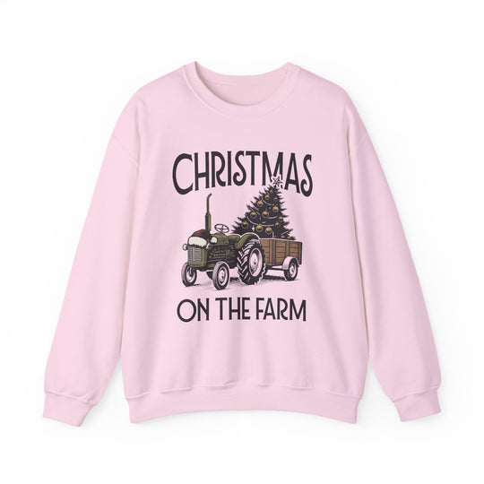 Light pink crewneck sweatshirt with CHRISTMAS ON THE FARM design, featuring a vintage green tractor and decorated tree, offering cozy comfort for colder months.