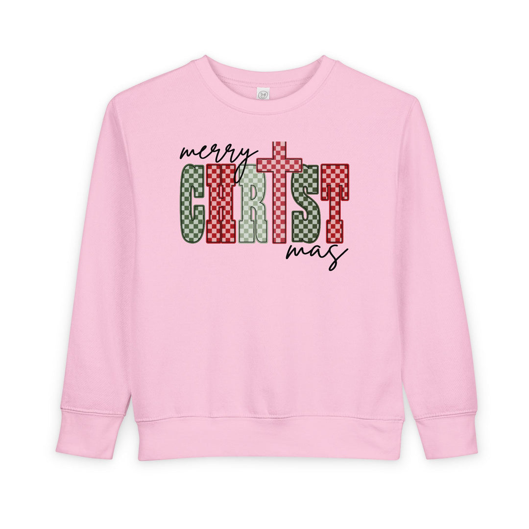 Christmas Toddler Crew sweatshirt in light pink with merry CHRISTmas featuring red and green checkerboard letters, designed for warmth and style in a soft fleece blend.