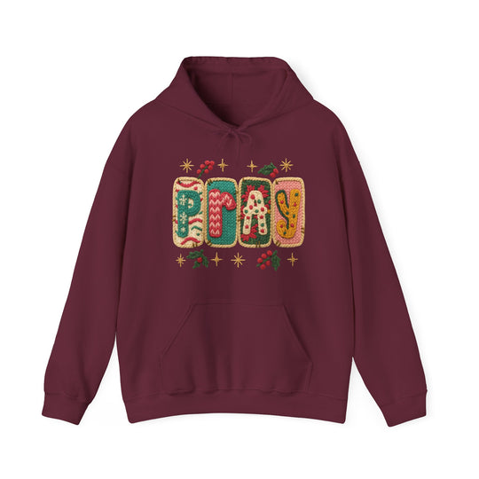 Maroon PRAY hoodie with festive knitted graphics, featuring a kangaroo pocket and drawstring hood, designed for warmth and comfort.
