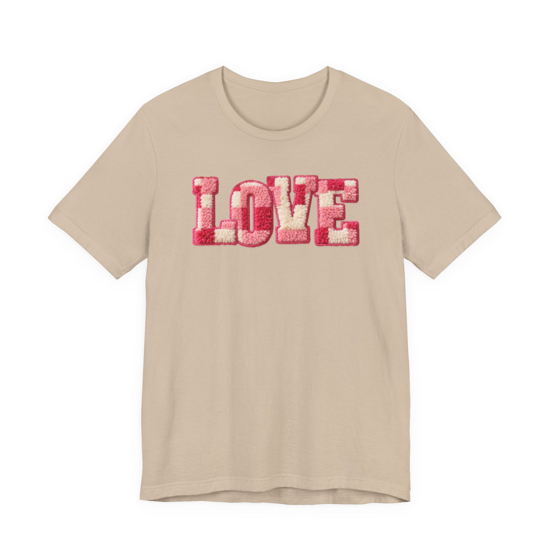 Light-beige Love Tee features chunky, tufted-yarn LOVE letters in pink and off-white. Soft cotton, unisex fit, ideal for those valuing comfort and style.