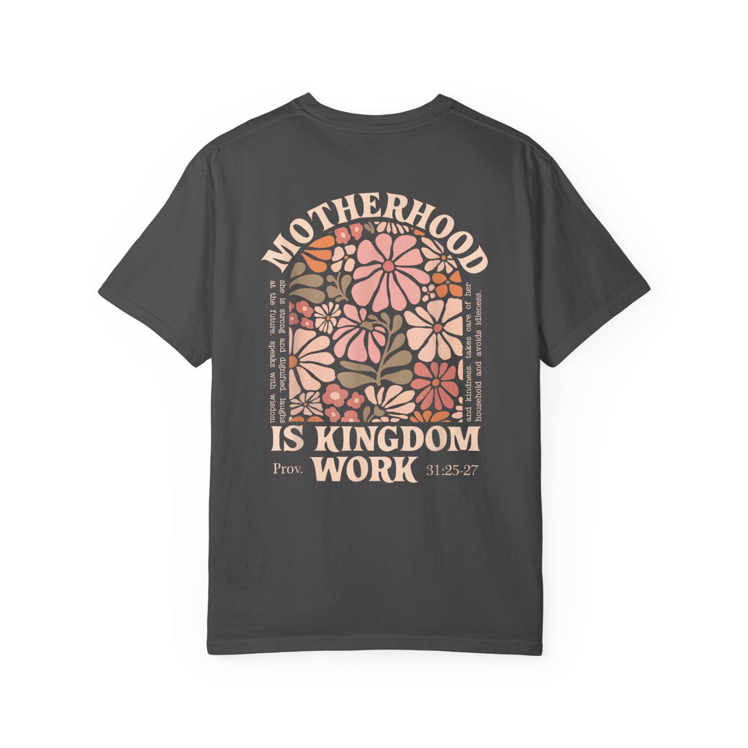 Back of dark charcoal Kingdom Work Tee with retro floral design and MOTHERHOOD IS KINGDOM WORK text, featuring Proverbs 31:25–27 snippets in small type.