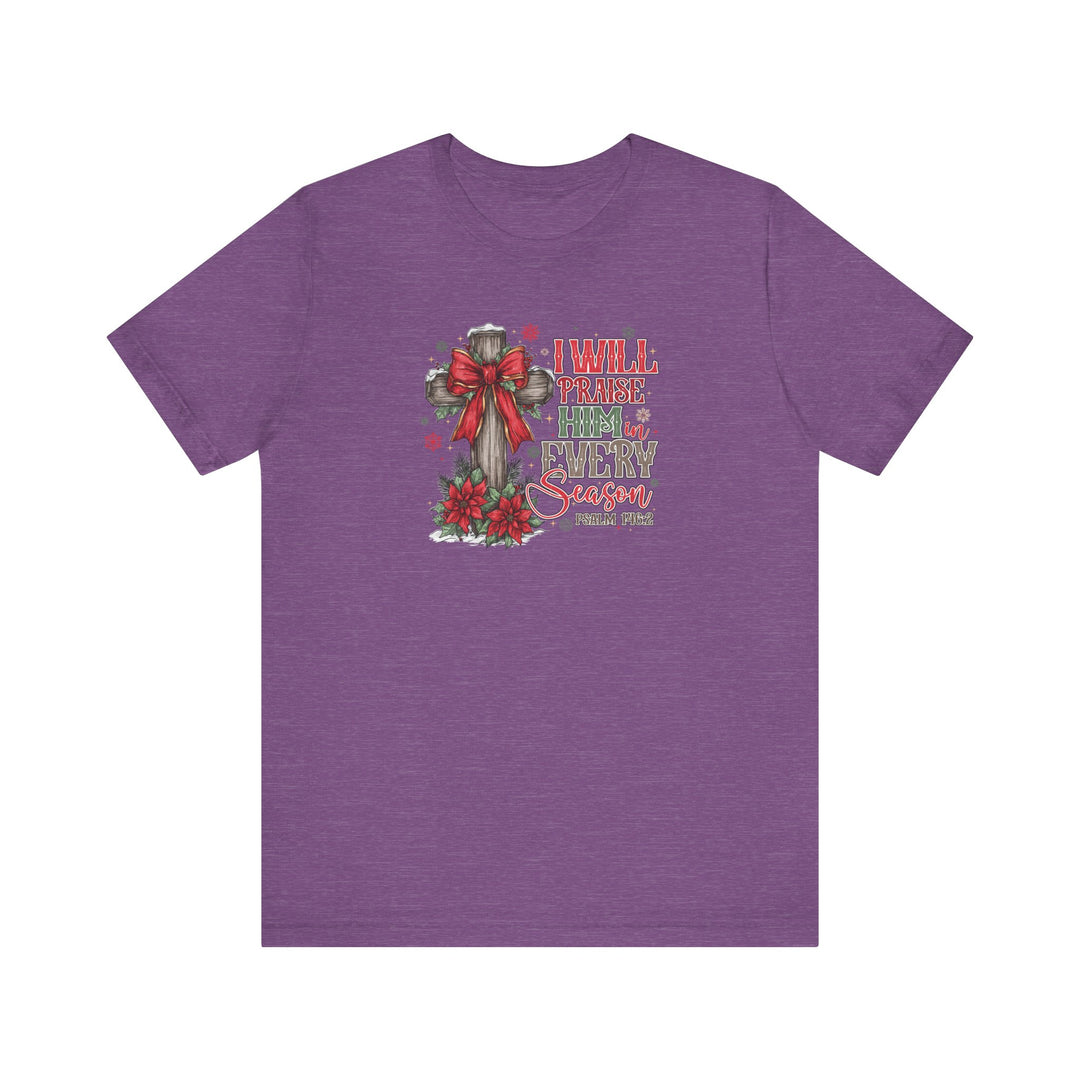 Purple T-shirt featuring a rustic cross with a red bow, poinsettias, and snow-dusted evergreens, captioned I WILL PRAISE HIM in EVERY Season from Faith Family Designs.