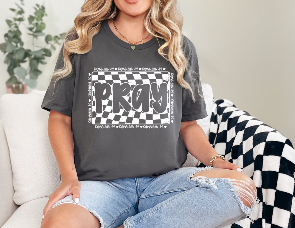Woman in torn jeans and gold bracelet wears a Pray Tee, a soft, unisex jersey short sleeve t-shirt, emphasizing comfort and style.