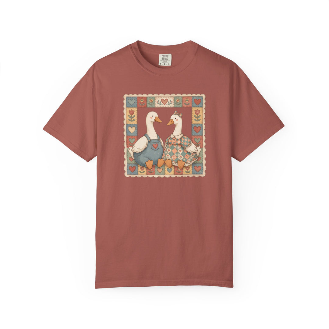 Thrifted Geese Tee features two geese in folk-art attire framed by heart and flower motifs, highlighting a cozy, relaxed fit in soft-washed, heavyweight cotton.