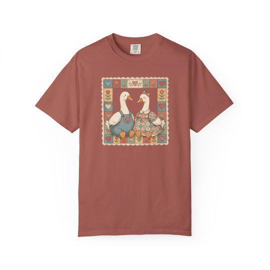 Thrifted Geese Tee features two geese in folk-art attire framed by heart and flower motifs, highlighting a cozy, relaxed fit in soft-washed, heavyweight cotton.