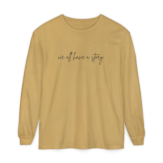 We all have a Story Long Sleeve Tee; tan, relaxed fit, 100% cotton, black text, ideal for casual wear.