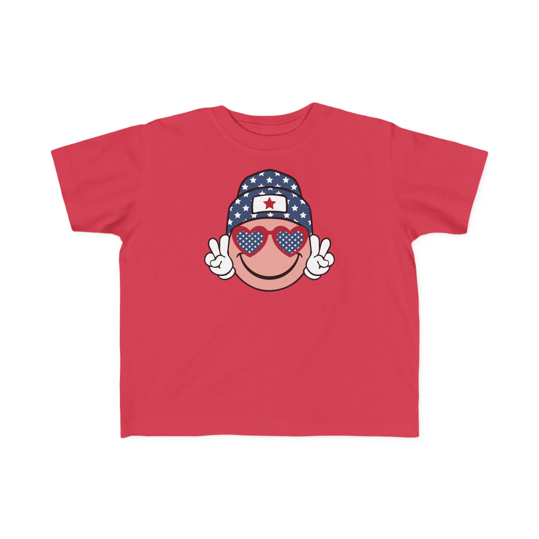American Girl Toddler Tee featuring a red shirt with a cartoon face, sunglasses, and hat. Soft 100% combed ringspun cotton, light fabric, tear-away label, classic fit. Sizes: 2T, 3T, 4T, 5-6T.