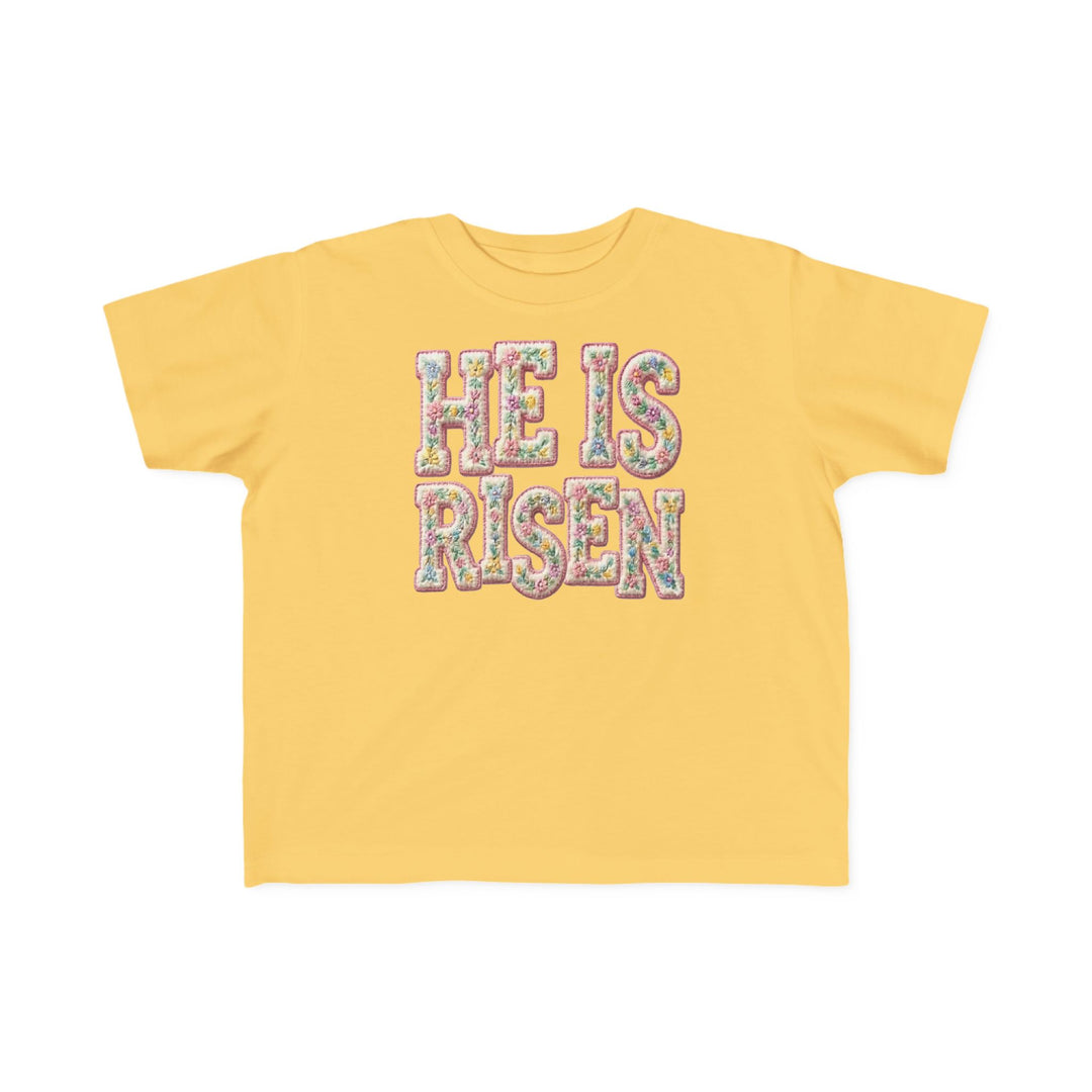 He is Risen Toddler Tee: Yellow short-sleeve shirt with 'HE IS RISEN' slogan in floral pattern, perfect for toddlers' sensitive skin.