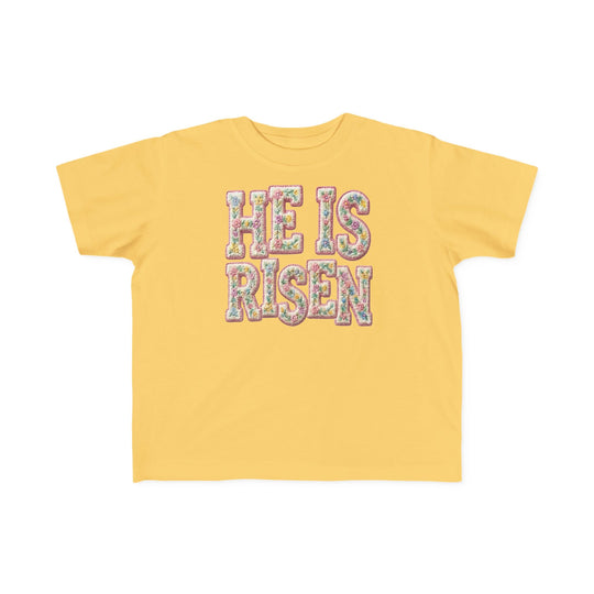 He is Risen Toddler Tee: Yellow short-sleeve shirt with 'HE IS RISEN' slogan in floral pattern, perfect for toddlers' sensitive skin.