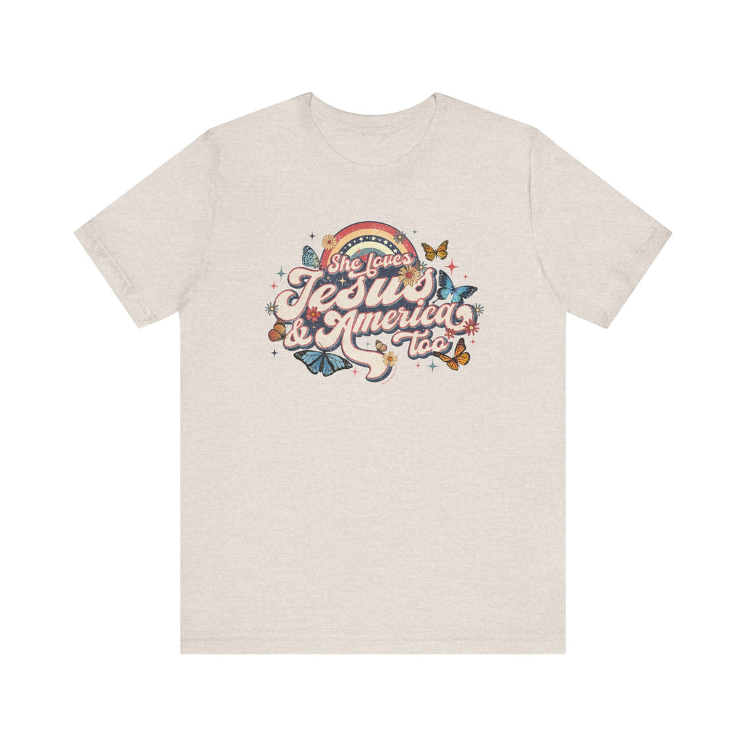 A white t-shirt featuring a graphic design of butterflies and flowers, titled She Loves Jesus and America Tee. Unisex jersey tee with ribbed knit collars, 100% Airlume combed cotton, and tear-away label.