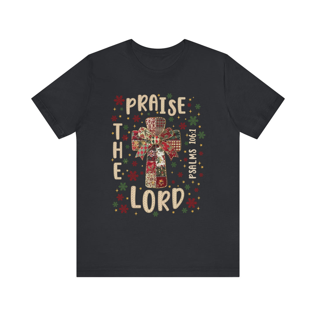 Praise the Lord Tee features a patchwork cross with a bow, surrounded by snowflakes and stars, and includes PSALMS 106:1. Crafted from soft cotton for comfort.