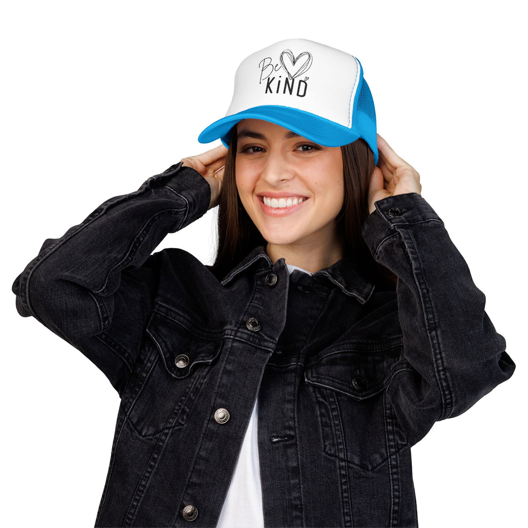 Young woman wearing a Be Kind Foam Trucker Hat, adjusting it with a smile. The hat features a structured, high-profile design with durable, breathable materials.