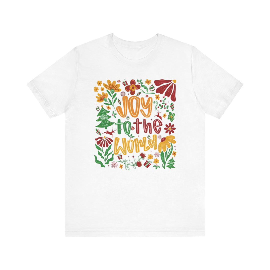 White crew-neck t-shirt featuring Joy to the World in colorful, festive hand-lettering, surrounded by holiday-themed illustrations. Soft, unisex fit from Faith Family Designs.