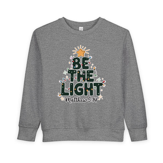 Gray crewneck sweatshirt featuring BE THE LIGHT in a Christmas tree shape with colorful lights and Matthew 5:14, designed for toddlers' comfort and style.