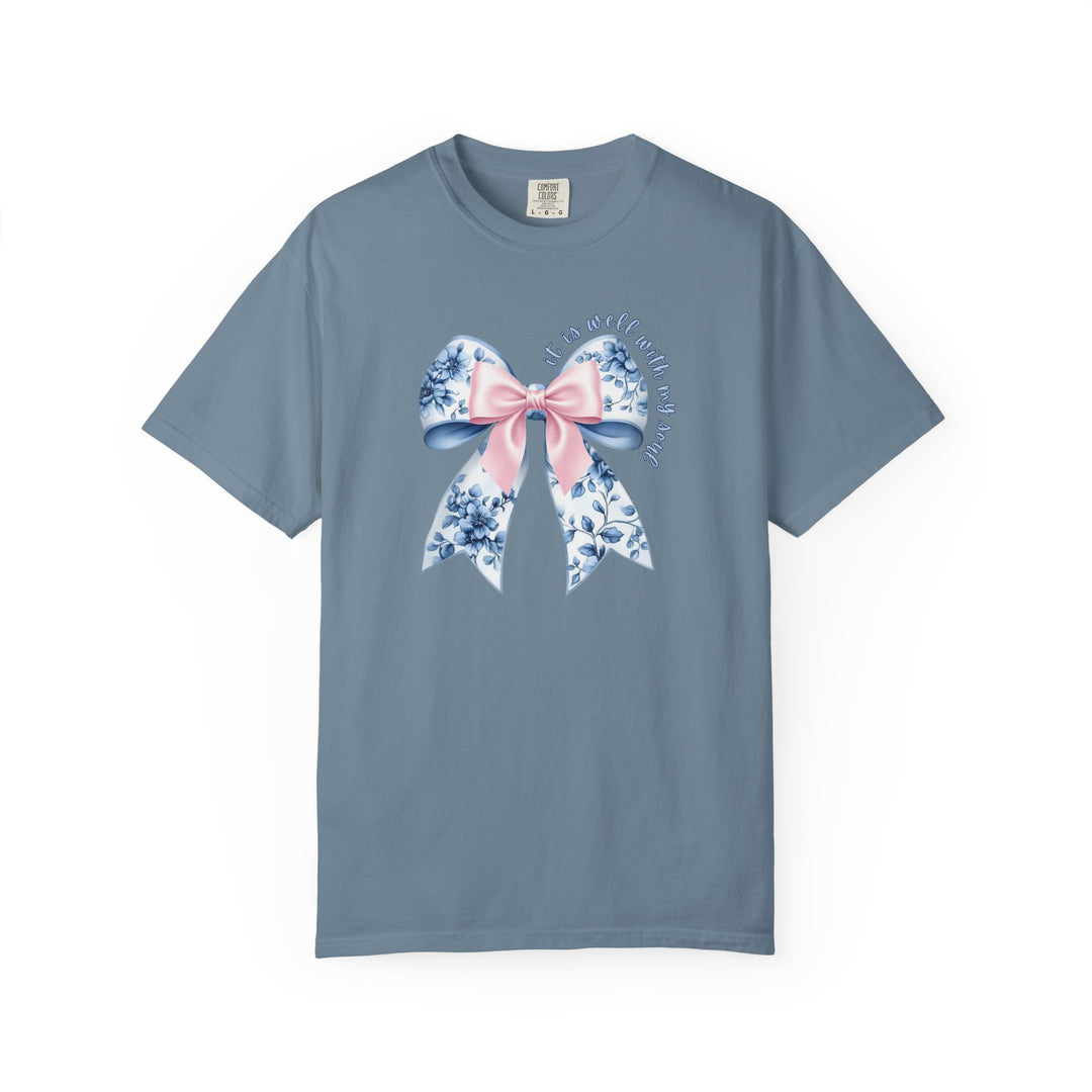 It is Well With My Soul Tee featuring a denim-blue color with a large bow graphic and inspirational text, offering a relaxed fit and luxurious comfort.