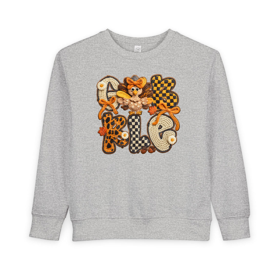 Gobble Toddler Crew: Light-gray sweatshirt with GOBBLE appliqué in plaid and leopard patterns, featuring a cartoon turkey and fall leaves, perfect for cozy autumn wear.