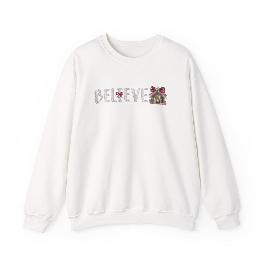 White crewneck sweatshirt with BELIEVE in patterned font, featuring red bows and a gingerbread house, embodying a simple holiday theme.