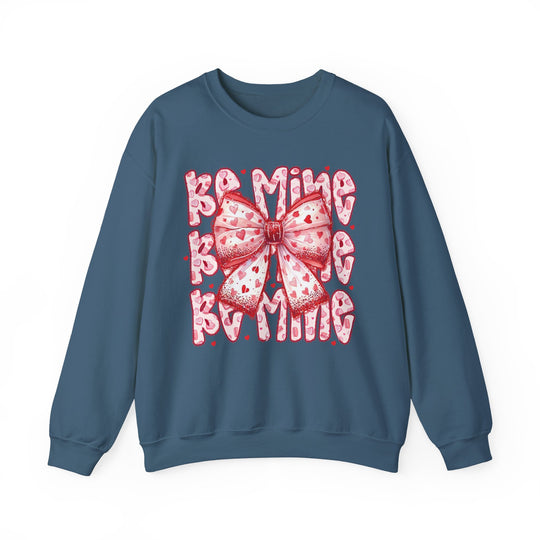 Teal crewneck sweatshirt with pink-and-red heart-patterned bow and BE MINE text, embodying a Valentine's Day theme. Ideal blend of comfort and style.